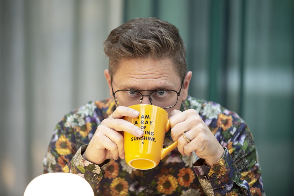 Yours truly drinking tea out of a bright yellow teacup.